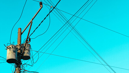 High steel power tower photographed against blue midday sky, illustrating energy distribution...