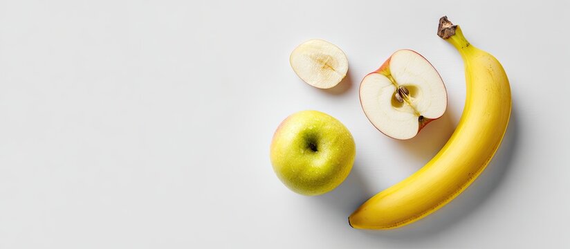 A whole banana, a green apple, and a red apple sliced in half sit on a white background