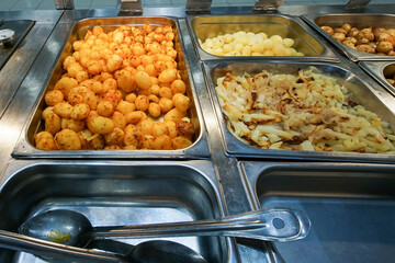  Hot potatoes of various preparations on metal trays are on sale.