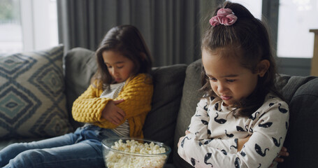 Sad girl, siblings or conflict with popcorn on sofa for fight, argument or disagreement in home....