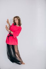The model is a young beautiful girl in a pink dress with a transparent skirt in a studio on a white...