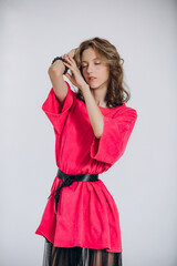 The model is a young beautiful girl in a pink dress with a transparent skirt in a studio on a white...