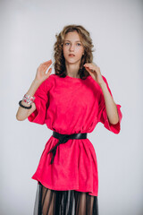 The model is a young beautiful girl in a pink dress with a transparent skirt in a studio on a white...