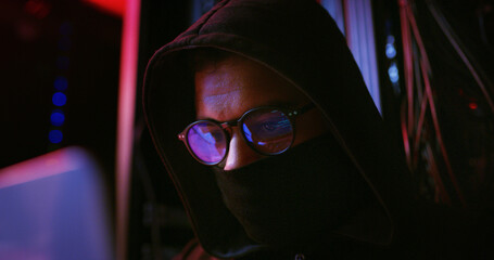 Night, glasses or man on laptop for hacking, programming or cybersecurity website. Software attack, late or hacker with mask in dark room for big data research, system update or online scam operation
