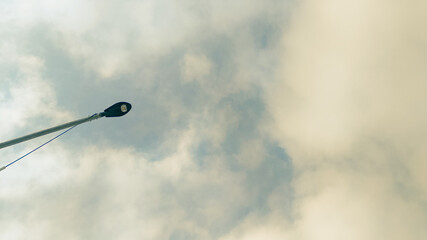 Contemporary lamppost silhouette set against bright sky with soft clouds, minimalistic city...
