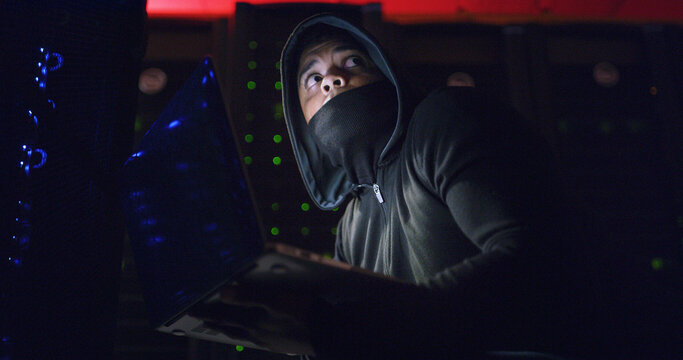 Night, scared and man on laptop for hacking, programming or cybersecurity website. Software attack, late or hacker with mask in dark room for big data research, cybercrime or online scam operation