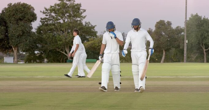 Completing run diverse teammates fist-bumping and walking toward pavilion carrying equipment basket