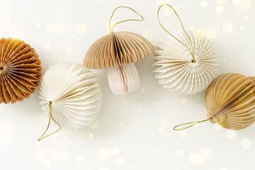 Paper Christmas Ornaments neutral pastel color, golden bokeh, Shining New Year decorations as mushroom, flashlights, Christmas baubles. Minimal aesthetic holidays, festive flat lay beige monochrome