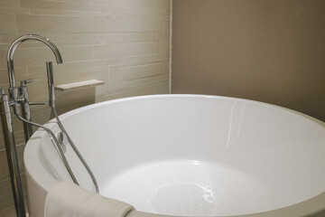 Modern circular bathtub with sleek chrome fixtures and neutral walls.