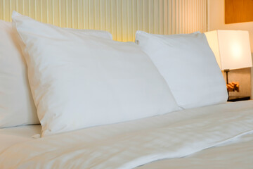 Clean white pillows on a neatly made bed with soft linens.