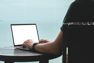 Work from anywhere concept, Person working on a laptop by the seaside, enjoying a serene view.