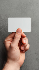 Hand holding a blank white credit card against a gray background