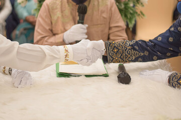 Handshake between groom and marriage guardian in an Islamic wedding ceremony, wearing traditional...