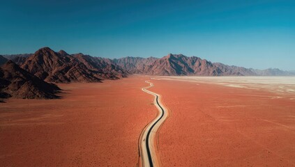 Desert highway winding through red terrain.  Vast, sun-drenched landscape