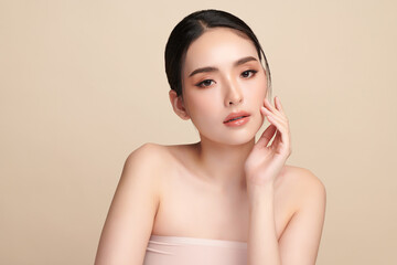 A beautiful young Asian woman with clean, fresh skin against a beige background. Skincare, facial...