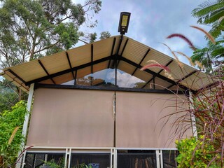 Eco-friendly minimalist house with triangular roof and solar-powered lamp, surrounded by lush...