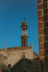 Obraz premium Majestic ancient stone tower reaching into a vibrant clear blue sky, showcasing historical architecture and timeless cultural heritage, a symbol of serene spiritual legacy.