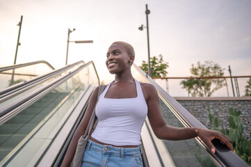 Young black woman going up on escalator in urban setting