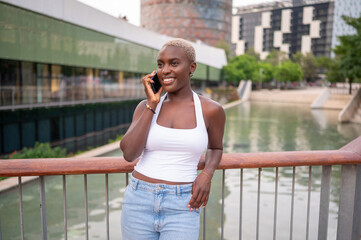 Young woman is making a phone call leaning on a railing in a city park
