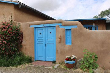 Honeysuckle Growing Near Adobe House with Turquoise Door and Hanging Chile Ristra located next to...