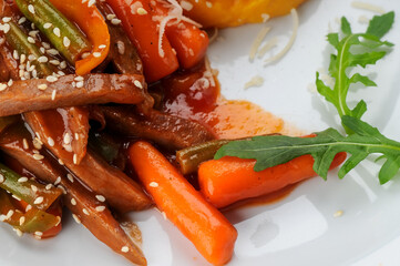 couscous with meat and vegetables in a white plate on a clean wooden background with arugula macro photo