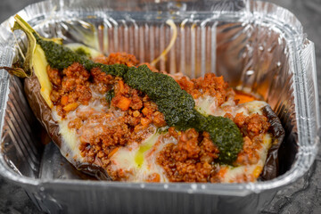 baked eggplant with cheese and meat in disposable dishes macro photo