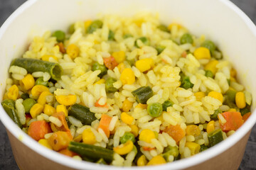 rice with vegetables in a disposable dish macro photo