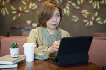 Fototapeta premium Woman is working on a tablet while sitting in a coffee shop