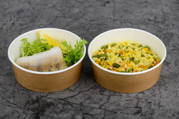 fish fillet with lyon and rice with vegetables in a disposable dish photo