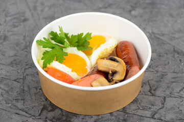 breakfast sausages egg mushrooms and tomatoes in disposable dishes