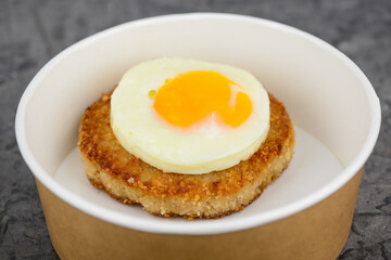 steak with fried egg on top in disposable dish macro photo