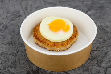 steak with fried egg on top in disposable dish