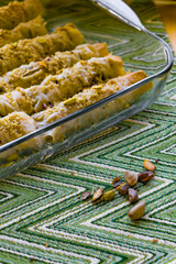The process of making homemade baklava in a cozy kitchen atmosphere.Ready-made baklava in the form of rolls, baked until golden brown and generously sprinkled with ground nuts, in a transparent form