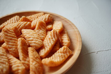 Crispy Japanese rice crackers piled on a wooden plate, ridged texture and warm color inviting a...