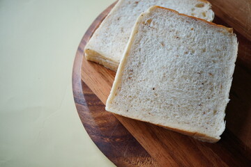 Two thick slices of soft white bread on a round wooden board, showing fluffy crumb and simple homemade comfort