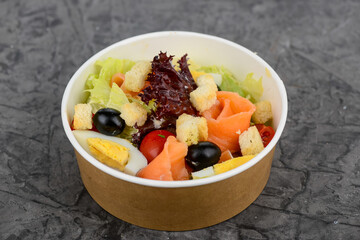 fresh vegetable salad with salmon in a disposable container
