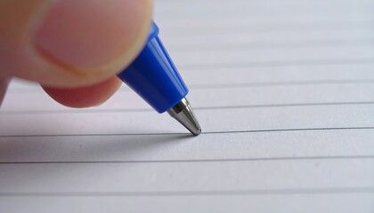 Close-up of a hand using a blue pen to write on lined paper