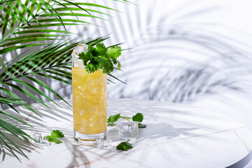 Yellow alcoholic cocktail drink with tequila, agave syrup, cilantro, jalapeno, lime juice and soda