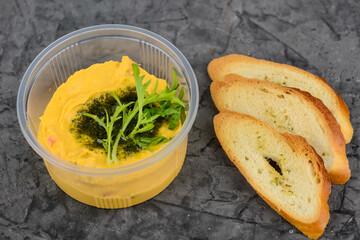 Light hummus snack in a disposable container with croutons