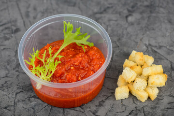 adjika appetizer in a disposable container with croutons