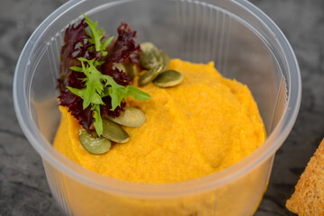 appetizer hummus from pumpkin in a disposable dish with croutons macro photo