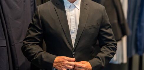 Businessman choose elegant suit in store. Hispanic businessman choosing tailoring and suit. Well-dressed male model in suit boutique, cropped view. Retail assistant help stylish man to find suit