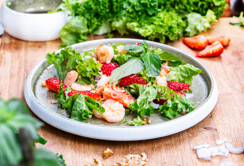 Fresh salad with lettuce and shrimps in cozy modern kitchen on wooden table