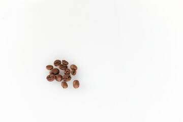 A small pile of roasted coffee beans lies on a clean white background, offering a simple and...
