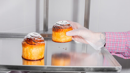 Gloved hand delicately arranges sugar-dusted buns, echoing bakery bliss and cozy Hygge moments,...