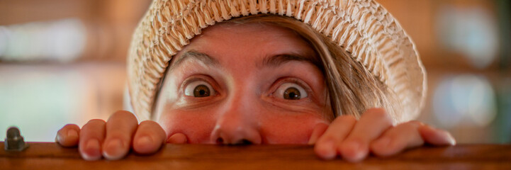 Eager eyes of a young Caucasian woman peeking playfully, embodying Hide and Seek Day magic, evoking...