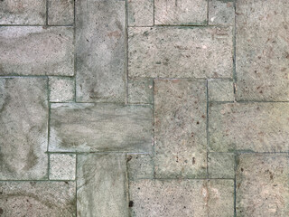 Monohcrome grey rectangular outdoor tiles with random shades and roughness. Suitable for exterior garden flooring. Seamless background texture.