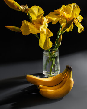Yellow irises in sunlight dance beside bananas, symbolizing renewal on Banna Baulin Festival and Iris Aurantiaco Celebration