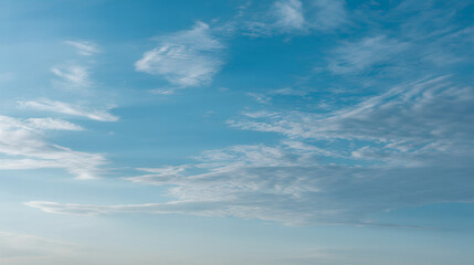 Soft scattered clouds fading into light blue sky