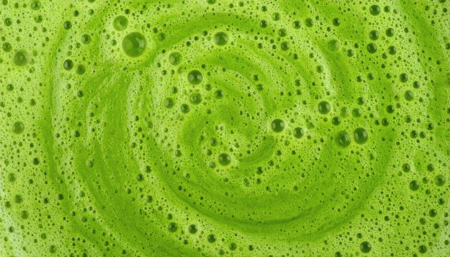 Vibrant green smoothie texture in a swirl, macro top view of a frothy healthy detox drink background.